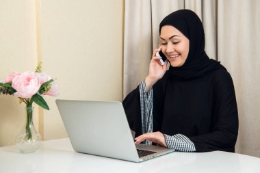 zarif çekici Müslüman kadın evde oturma odasında online alışveriş bilgi arama mobil dizüstü bilgisayar kullanarak