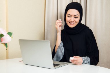 Türban veya onun Smartphone cep telefonu ile müzik dinlemek için dinleme hijab genç ve çekici Müslüman kadının portresi.