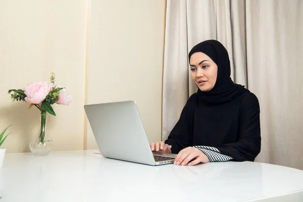 Elegante mujer musulmana atractiva usando portátil móvil que busca información de compras en línea en la sala de estar en casa — Foto de Stock