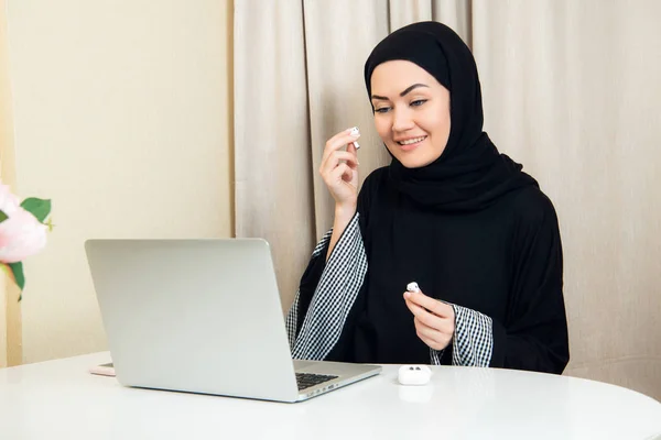 En arabisk kvinna med moderna trådlösa hörlurar för att lyssna på musik. Hon vilar hemma. — Stockfoto