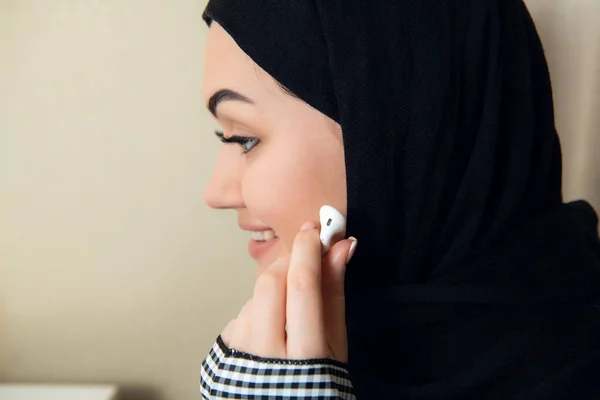 Retrato de una joven y atractiva musulmana con turbante o hiyab escuchando música en streaming en su smartphone . — Foto de Stock