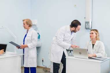 Neşeli tıbbi takım diş Office uygulama ve hastaların listesini inceleyerek hakkında tartışmak.