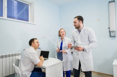 Sağlık personeli dizüstü ve tablet pc kullanarak tıbbi raporlar üzerinde tartışıyor. Sağlık çalışanlarına hastane ofiste tartışma