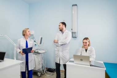 Neşeli tıbbi takım diş Office uygulama ve hastaların listesini inceleyerek hakkında tartışmak.