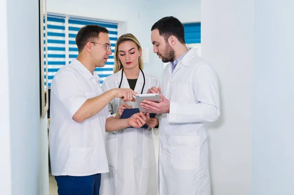 Vista de ángulo alto de tres médicos con batas blancas conversando en la sala del hospital — Foto de Stock