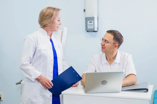 Médico y enfermera revisando la información del paciente en una computadora portátil en un entorno de oficina — Foto de Stock