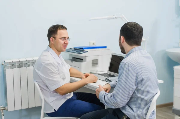 Médico masculino discutiendo informes con el paciente en el escritorio en el consultorio médico — Foto de Stock