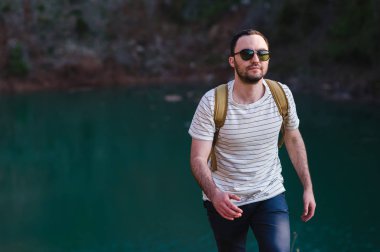 Doğada yürüyüş sırt çantası ile adam portre hiking. Beyaz adam yaz gezisi sırasında mutlu orman arka planda ile gülümseyen