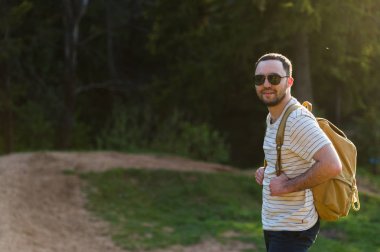 Doğada yürüyüş sırt çantası ile adam portre hiking. Beyaz adam yaz gezisi sırasında mutlu orman arka planda ile gülümseyen