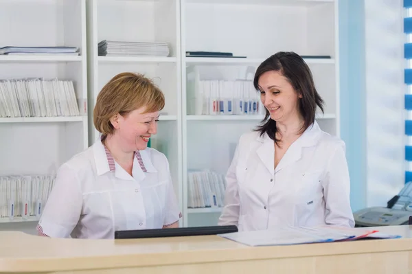 Dos enfermeras sonrientes trabajando en la recepción del hospital —  Fotos de Stock