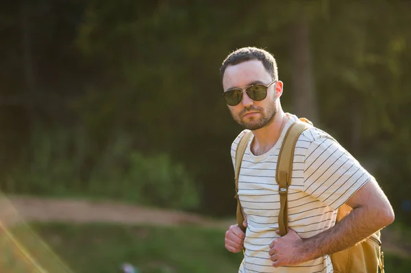 Viajes, turismo, aventura, senderismo y concepto de personas - hombre barbudo con mochila senderismo en el bosque y respira aire puro en un día soleado . — Foto de Stock