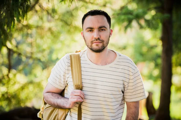 Senderismo retrato de hombre con mochila caminando en la naturaleza. Hombre caucásico sonriendo feliz con el bosque en el fondo durante el viaje de verano — Foto de Stock