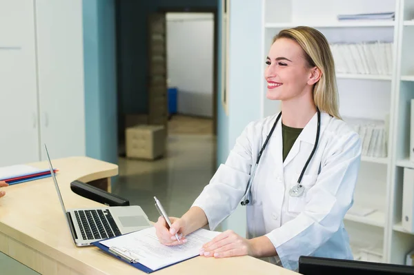 Jovem recepcionista do sexo feminino conversando com o paciente cliente no hospital — Fotografia de Stock