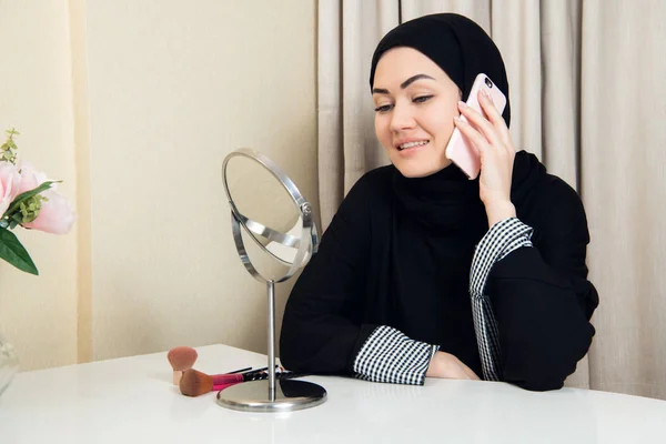 Iloinen onnellinen kaunis musliminainen istuu ja käyttää matkapuhelinta kutsuen ystävä chattailuun loman aikana . — kuvapankkivalokuva