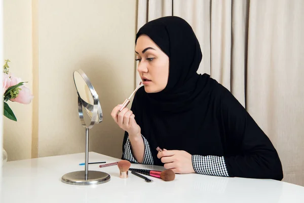 Retrato de una mujer árabe saudí pintándose los labios con un lápiz labial en casa — Foto de Stock