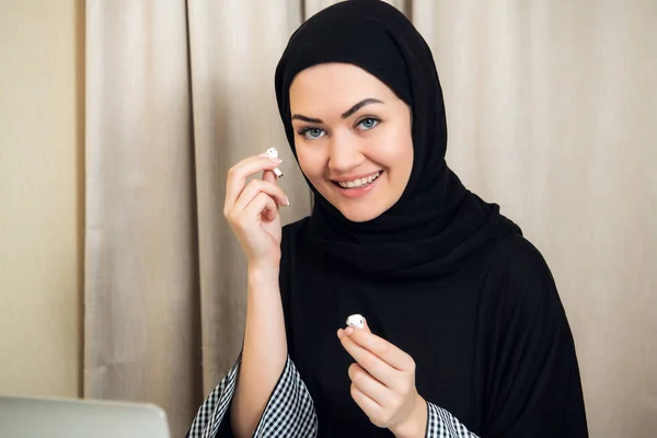 Mujer árabe en hijab escucha música en auriculares inalámbricos en casa u oficina . — Foto de Stock