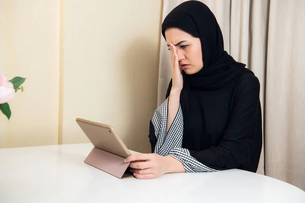 Triste musulmana ocupada mujer de negocios sosteniendo una tableta en casa u oficina — Foto de Stock