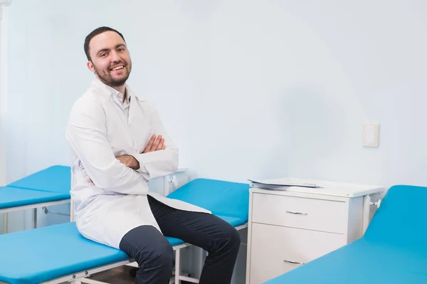 Retrato de jovem homem sorridente no uniforme perto de sofás de massagem — Fotografia de Stock