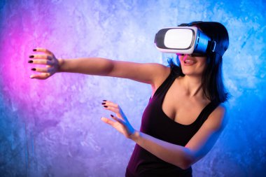 Sanal gerçeklik kulaklık giyen güzel yanlısı bir oyun kız Online Video oyun, el hareketi çalış. Odaya Cool Retro Neon renkler