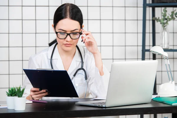 Mujer asistente de laboratorio trabajando en su escritorio, hospital, documentos — Foto de Stock