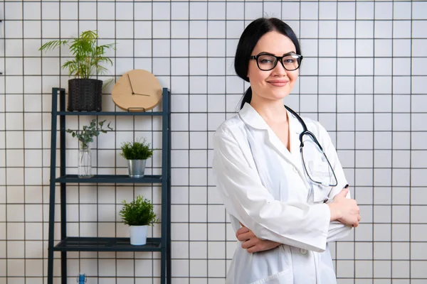 아름다운 웃는 의사 옷을 입고 현대식 사무실에 서 있는 모습 — 스톡 사진