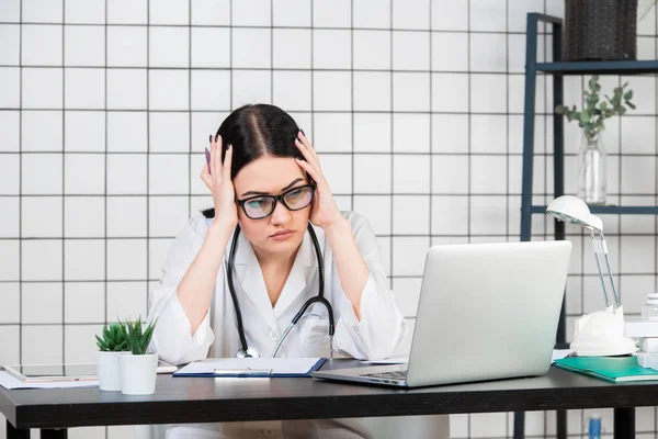 Desperate female doctor sitting at her office — Stock Photo, Image