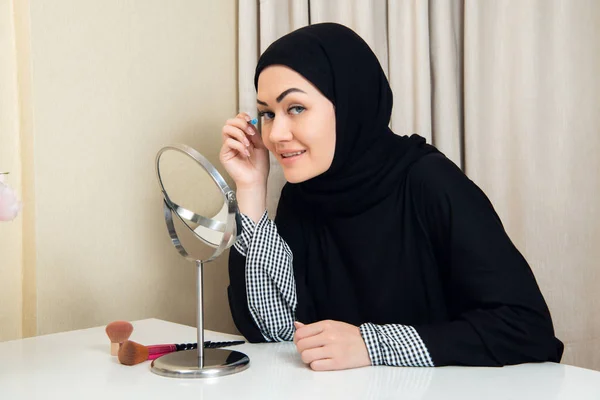Arabi nainen soveltamalla meikki hänen kasvonsa, yllään perinteinen arabialainen mekko — kuvapankkivalokuva