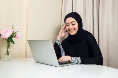 zarif çekici Müslüman kadın evde oturma odasında online alışveriş bilgi arama mobil dizüstü bilgisayar kullanarak