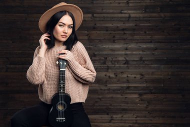 Gitar çalmak ve gülümseyen genç kadın. Müzik konsepti. Arka plan üzerinde ev atmosfer.