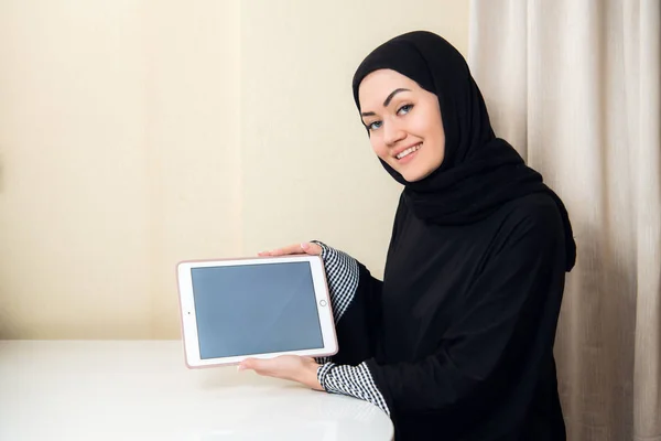Mujer musulmana sosteniendo la tableta con pantalla en blanco en casa u oficina. Concepto de copyspace tecnológico — Foto de Stock