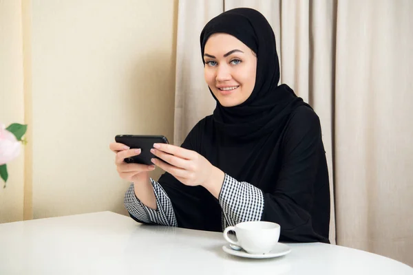 Mujer árabe bastante moderna jugando en el teléfono inteligente en casa — Foto de Stock