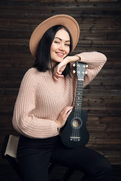 Νεαρή γυναίκα παίζει κιθάρα και να χαμογελά. Μουσική αντίληψη. Η ατμόσφαιρα του σπιτιού στο φόντο. — Φωτογραφία Αρχείου