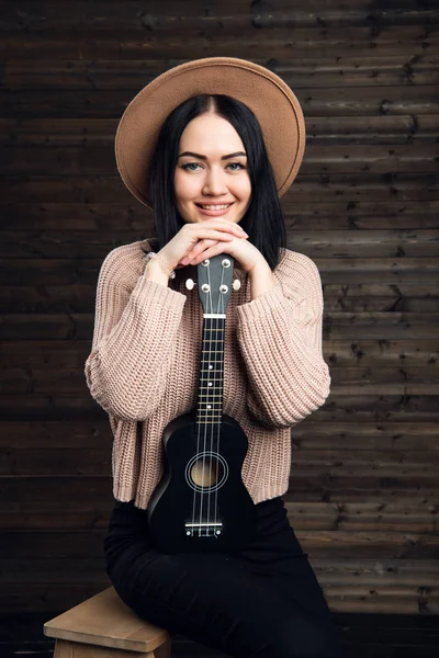 Ung kvinna spelar gitarr och leende. Musik-konceptet. Hem atmosfär på bakgrund. — Stockfoto