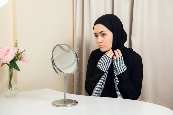 Hermosa mujer musulmana mirando al espejo y poniendo su bufanda . — Foto de Stock