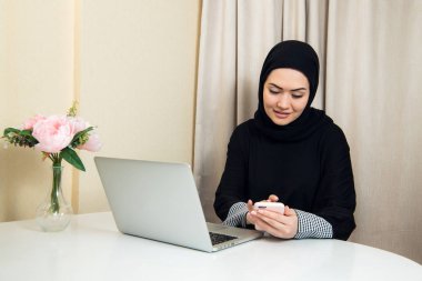 Evde bir akıllı telefon kullanan Arap mutlu rahat kadın