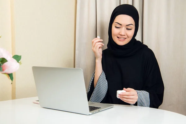 Porträtt av en ung och attraktiv muslimsk kvinna i en turban eller hijab Lyssna på strömmande musik på sin smartphone. — Stockfoto