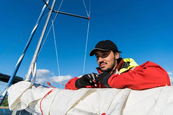 Sailor man at boat bow with cap looking away the sea while sailing