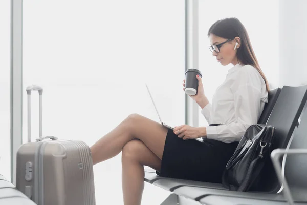 Mujer disfruta del ordenador portátil y bebe café en la terminal del aeropuerto —  Fotos de Stock