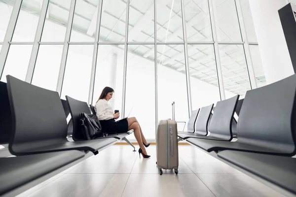Fiatal női utas a repülőtéren, használja a táblagépét, miközben várja a járatát. — Stock Fotó