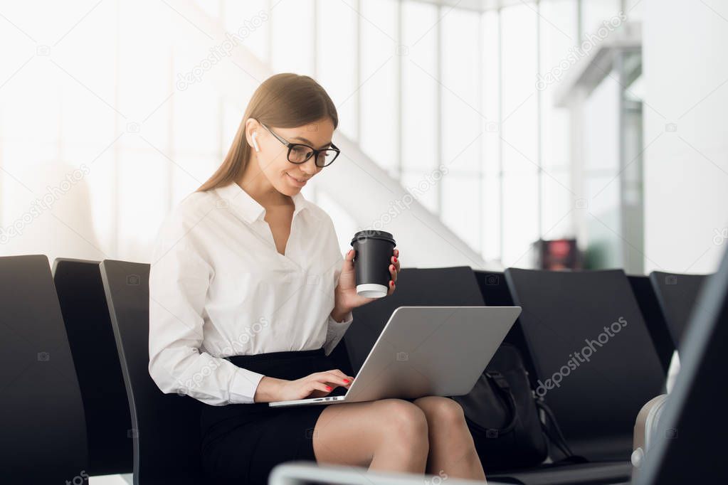 Beautiful business woman working on laptop while waiting for her flight in an airport