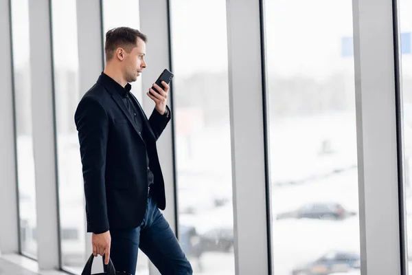 Koncentrerad affärsman spelar in röstmeddelande på flygplatsen — Stockfoto