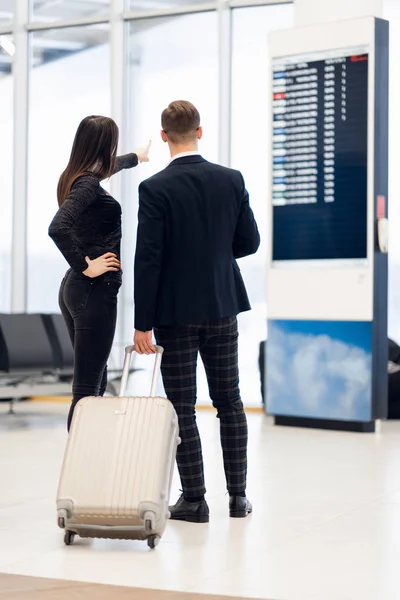 Üzleti pár nézi a menetrendet gazdaság beszállókártya a repülőtéren — Stock Fotó