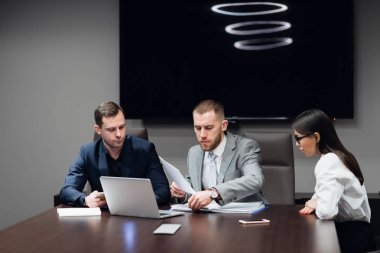 İş adamları toplantı odasında dizüstü bilgisayarlarıyla birlikte çalışıyorlar.