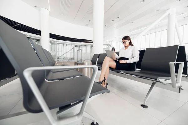 Joven mujer de negocios con estilo que trabaja con su computadora portátil en el aeropuerto —  Fotos de Stock