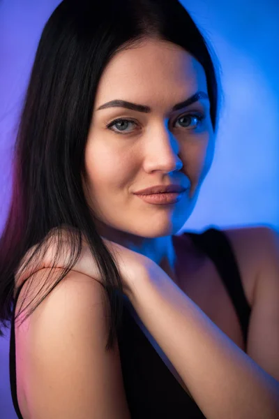 Σέξι νεαρή γυναίκα πορτρέτο, σε πολύχρωμο φόντο. Σαγηνευτικό μελαχρινή μοντέλο κορίτσι σε μαύρο σέξι ρούχα, φωτεινό μακιγιάζ στο φως νέον. Κλάμπερ, νυχτερινή ζωή — Φωτογραφία Αρχείου