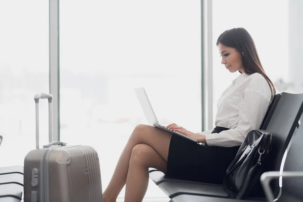 Mujer de negocios usando laptop en el aeropuerto sentada en la ventana —  Fotos de Stock