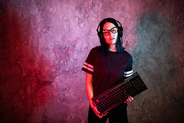年轻女子，键盘摆设在墙前，闪烁着红色的霓虹灯。 游戏玩家. — 图库照片