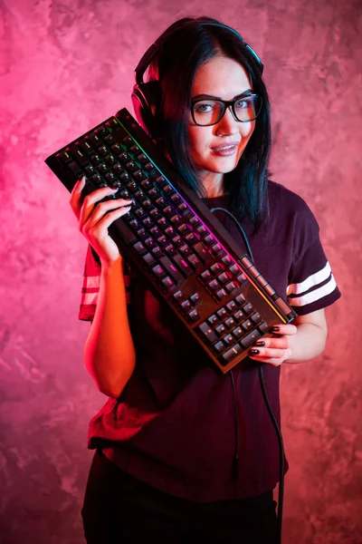 Όμορφη επαγγελματίας gamer κορίτσι με πληκτρολόγιο. Χαριτωμένο σπασικλάκι που φοράει γυαλιά και χαμογελάει. Cyber e-Sport Πρωτάθλημα Διαδικτύου. — Φωτογραφία Αρχείου