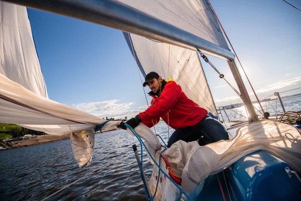 Yacht sailor pulling rope. Man working on sailboat.