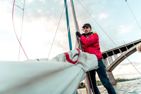 Yacht sailor pulling rope. Man working on sailboat.